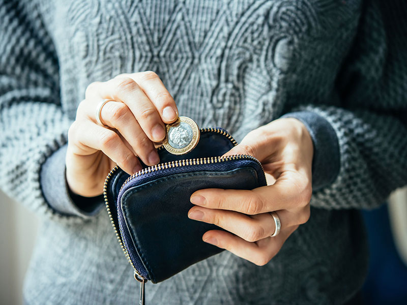 Femme déposant une pièce de monnaie dans un portefeuille.