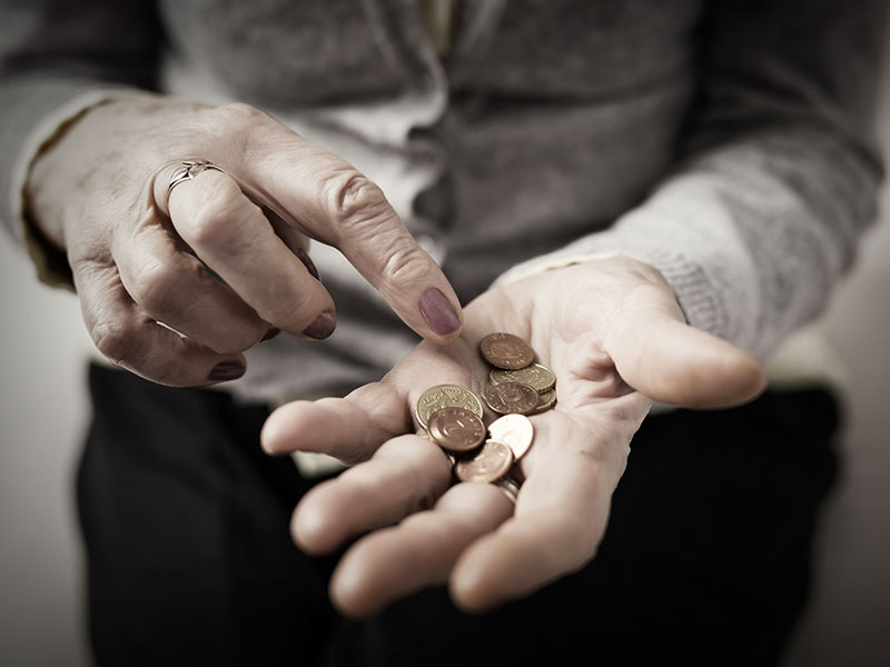 Personne âgée comptant des pièces de monnaie qu'elle tient dans sa main.