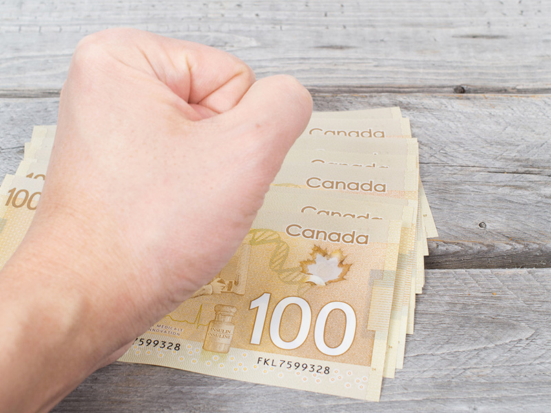 Poing sur une pile de billets de banque canadiens.
