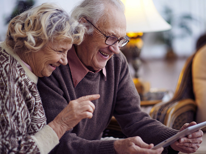 Couple retraité s'amusant à regarder une tablette.