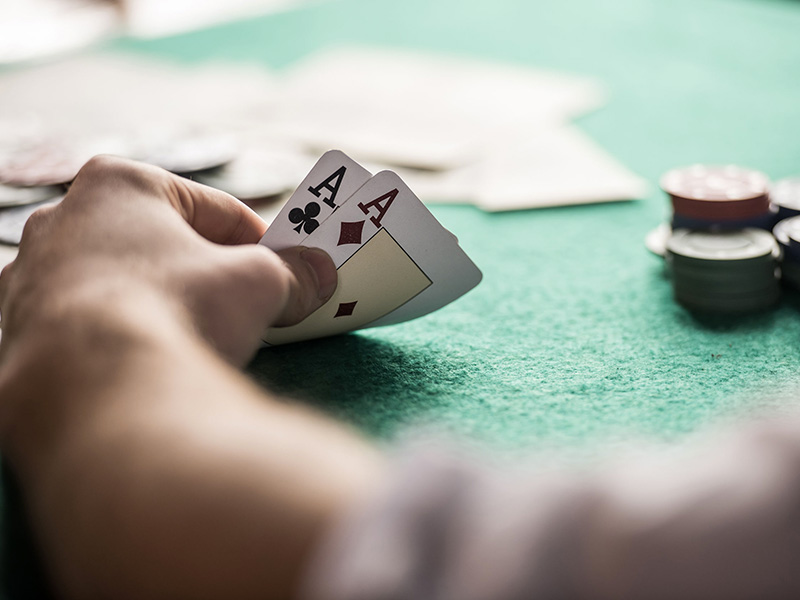 À une table de poker, gros plan d'une main tenant une paire d'as.