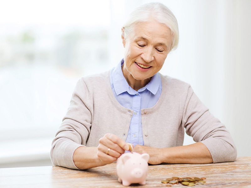 Femme âgée déposant une pièce de monnaie dans une tirelire.
