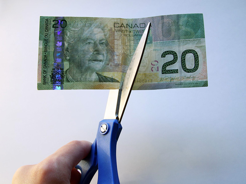 Billet de 20 dollars canadiens coupé en deux avec des ciseaux.