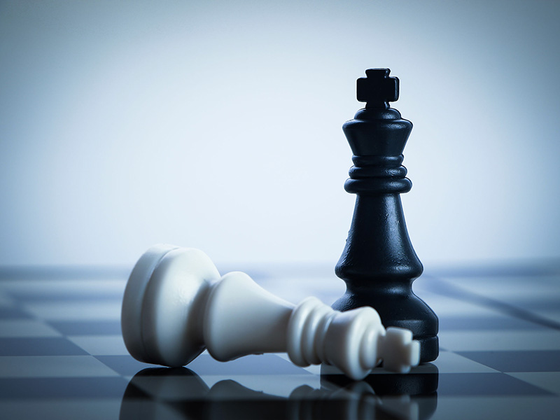 Deux pièces d'un jeu d'échec : le roi blanc renversé, le roi noir, debout.
