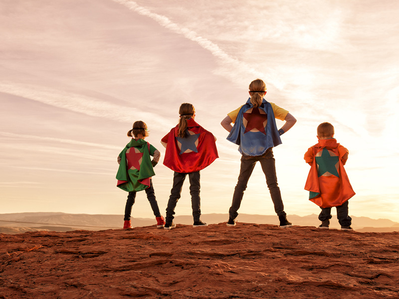 Un groupe de quatre jeunes enfants habillés en superhéros.