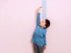 Jeune garçon mesurant sa taille contre un mur.