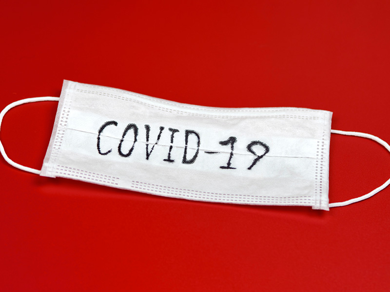 Masque chirurgical sur lequel il est écrit COVID-19