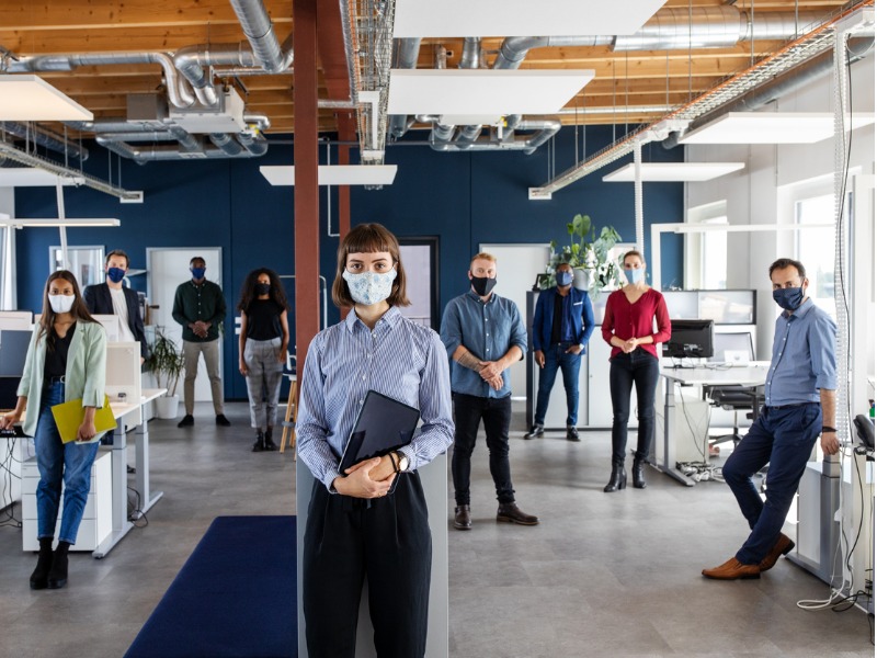 Plusieurs travailleurs masqués dans un bureau.