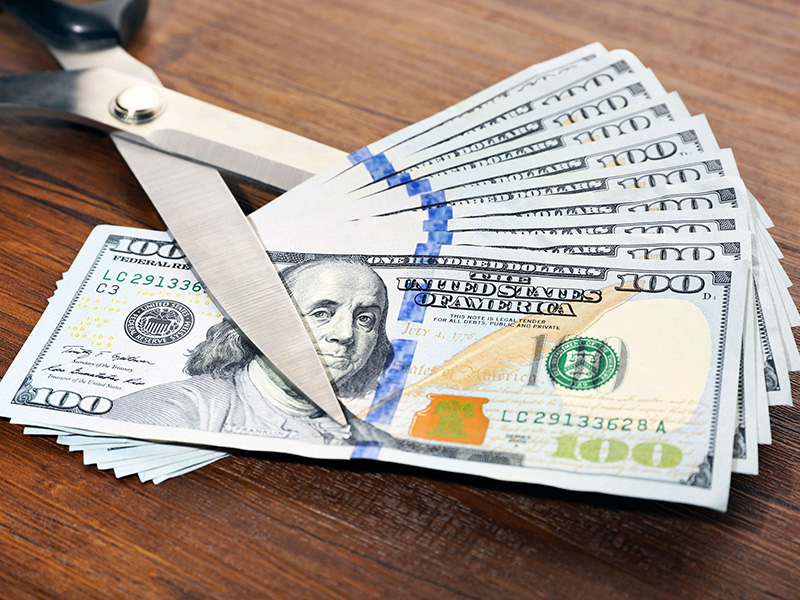 Couper une liasse de billets de banque avec des ciseaux.
