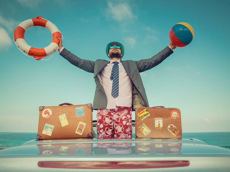 Homme d'affaires en vacances, avec une bouée de sauvetage et un ballon de plage dans les mains.