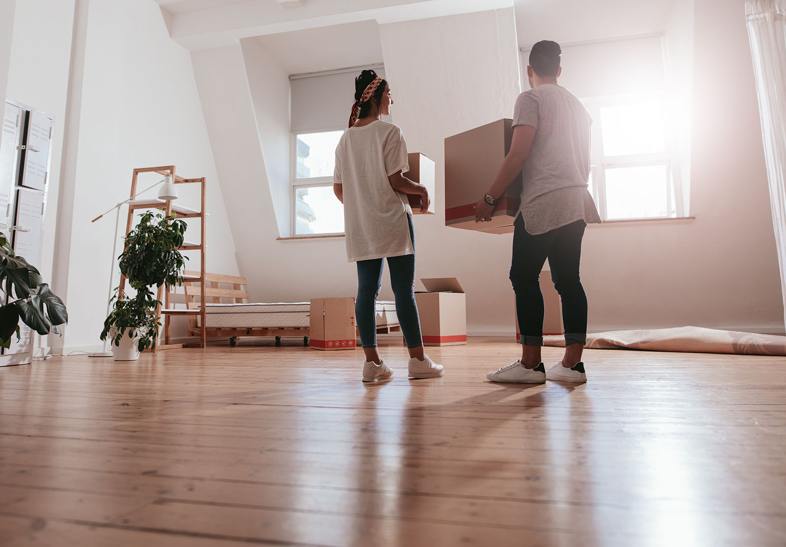 Vue arrière d'un jeune couple transportant des cartons dans une nouvelle maison. Jeune homme et jeune femme tenant des cartons et déménageant dans une nouvelle maison.