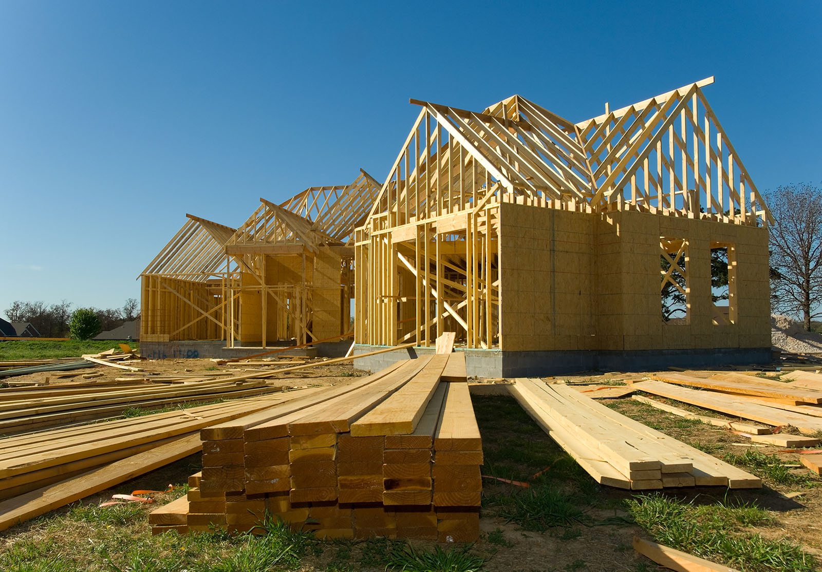 Maison neuve en construction avec bois, fermes et fournitures sur fond de ciel bleu
