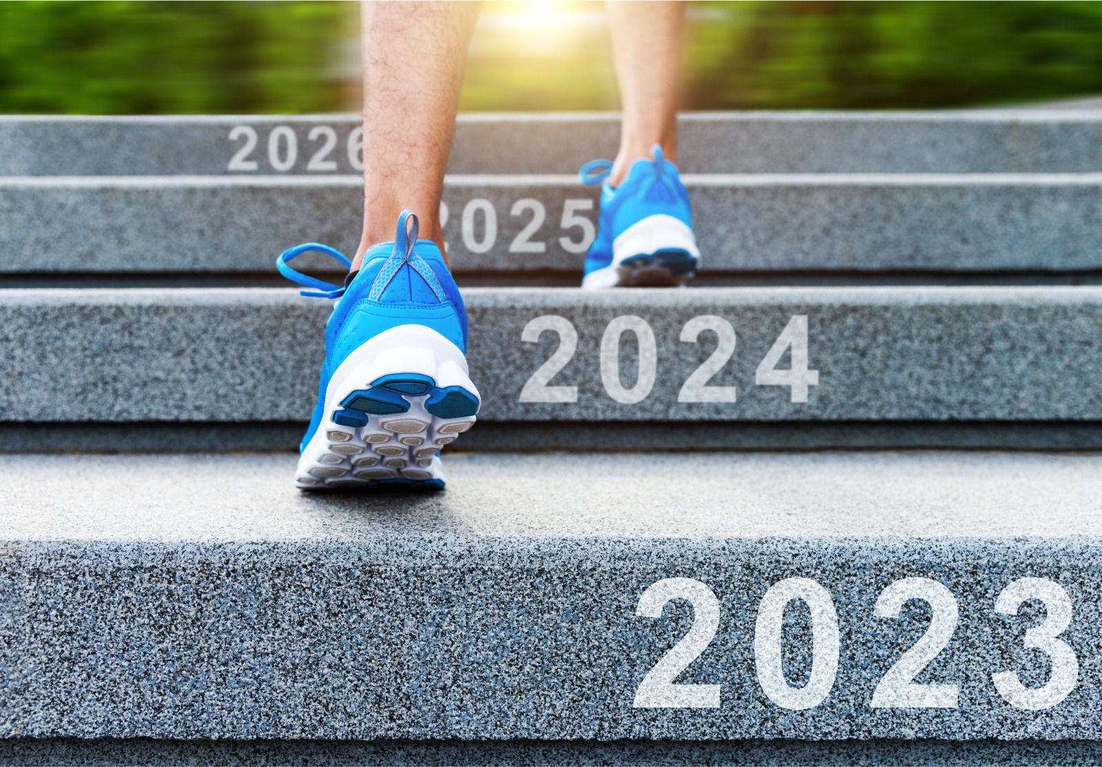 Section basse de l’homme montant les escaliers avec le numéro du nouvel an 2023, 2024, 2025 et 2026.